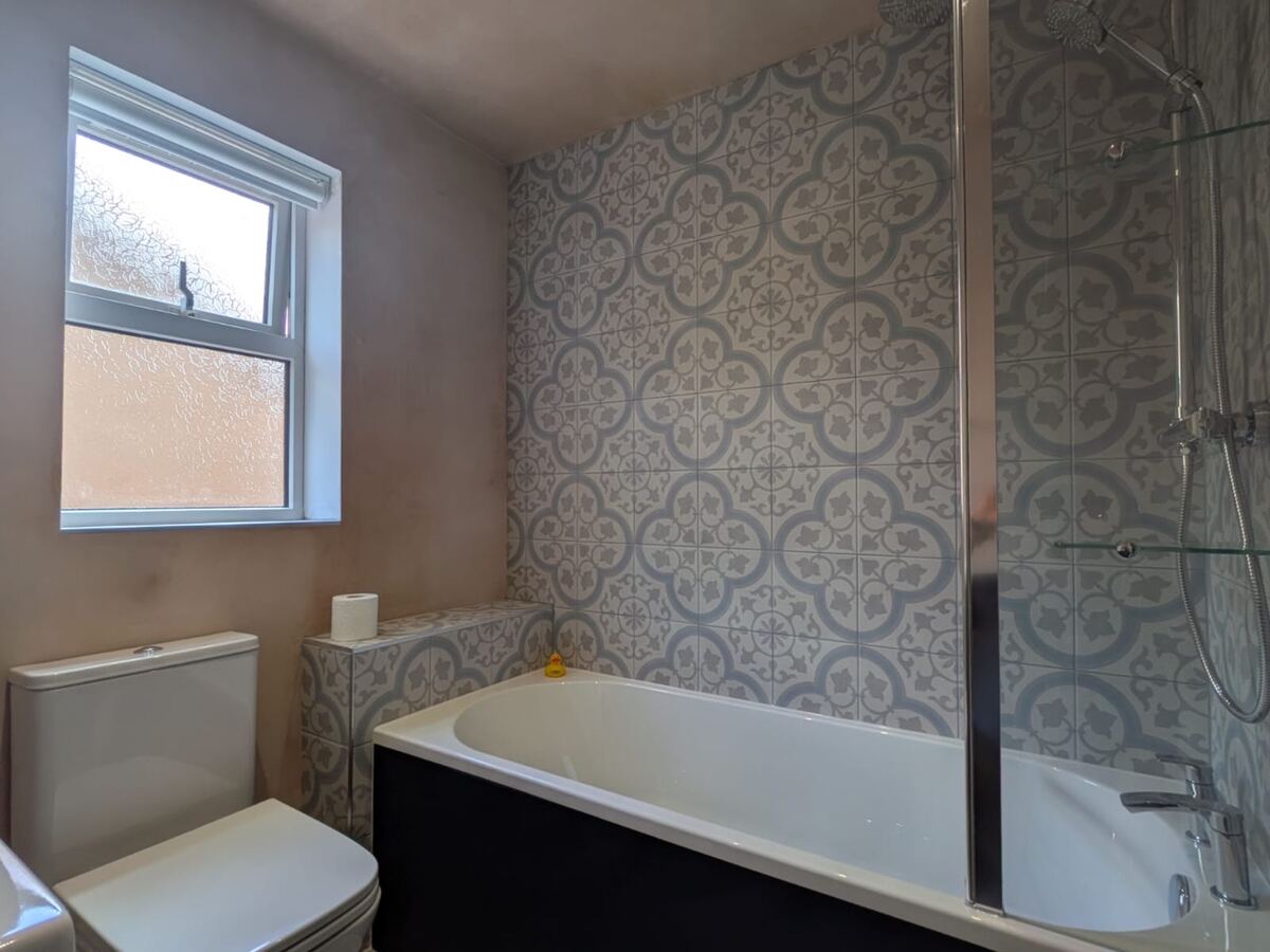 Bath with decorative patterned wall tiles and glass shower screen
