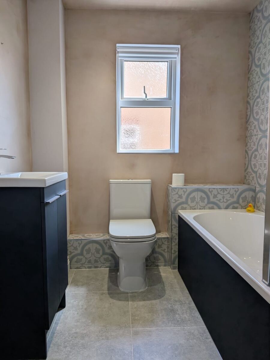 Bathroom with dark vanity, toilet and decorative patterned tiles
